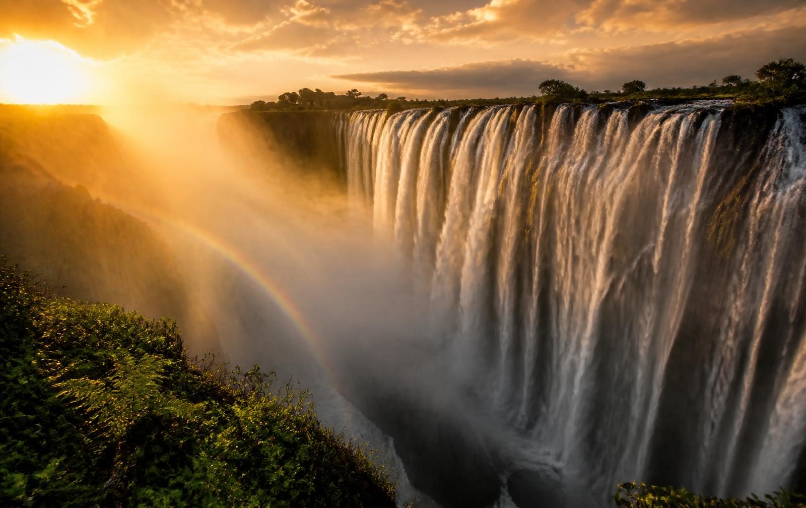 Victoria Falls at golden hour, spray rising through the gorge
